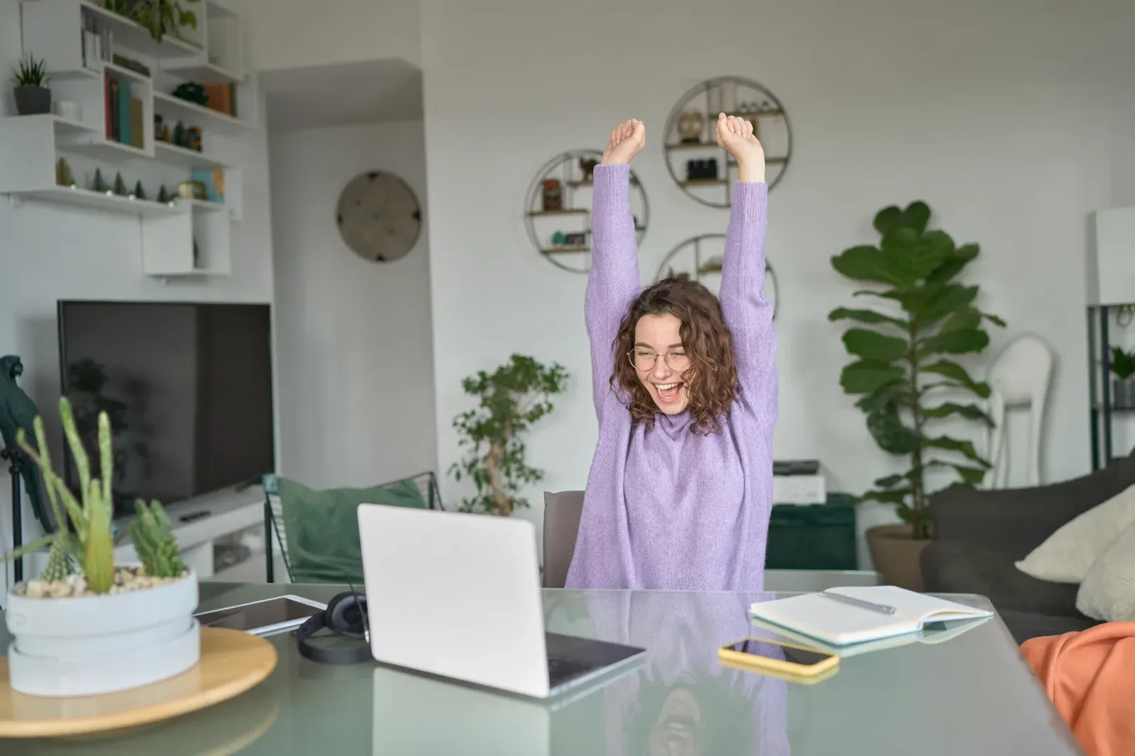 Una colaboradora celebra frente a su computadora tras una solicitud aprobada.